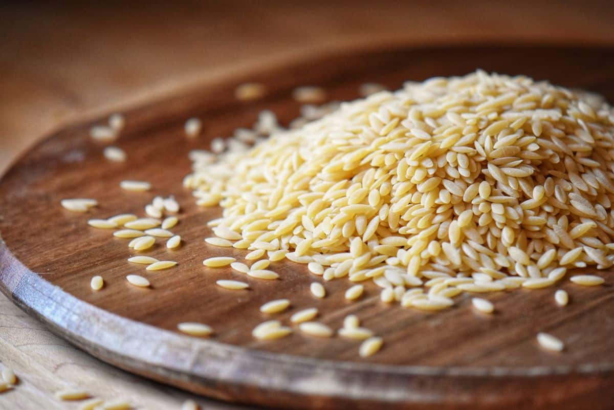 Orzo pasta on a wooden board.