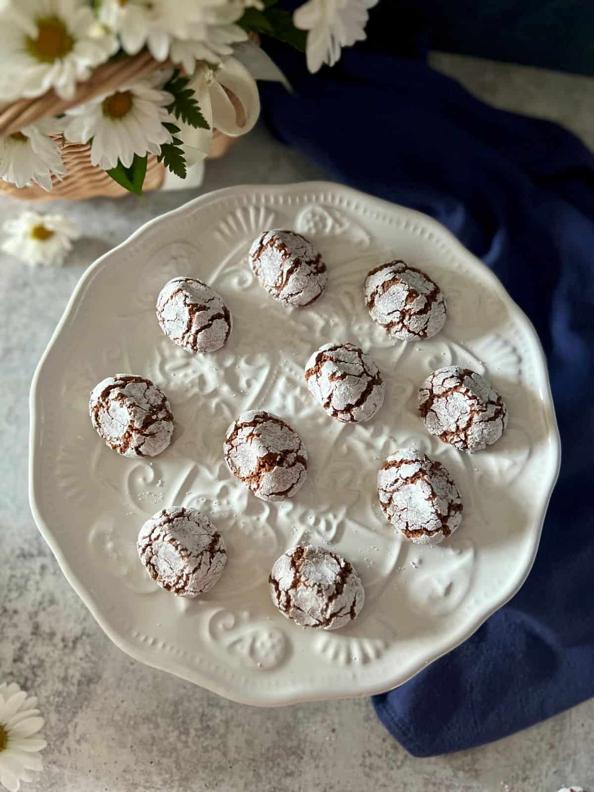 The snow-white, crackly tops of chocolate amaretti cookies on a white platter